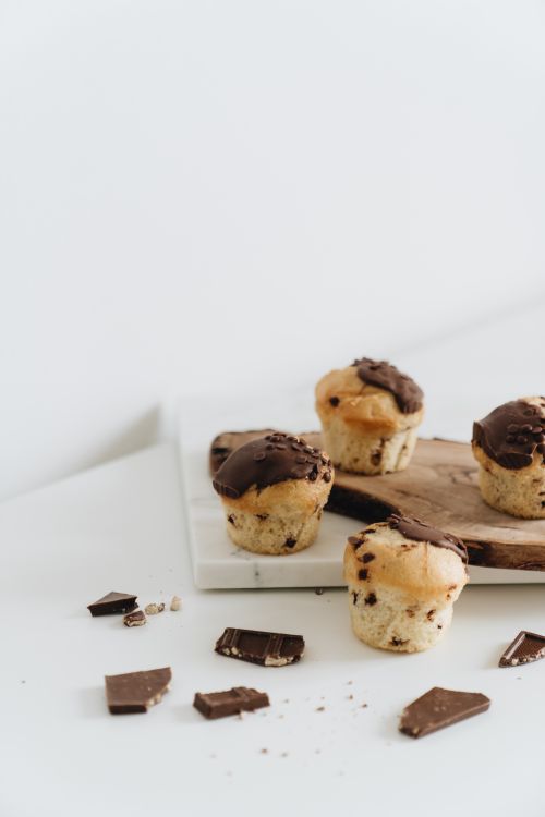 Free Tasty chocolate chip muffins on a wooden board, perfect for indulgent snacking. Stock Photo