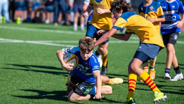 Dynamic action shot of young rugby players competing on a sunny day.