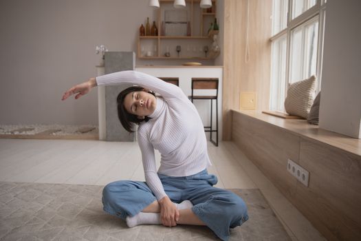 女子在室内以侧伸瑜伽姿势进行表演，强调在舒适的环境中放松和健身