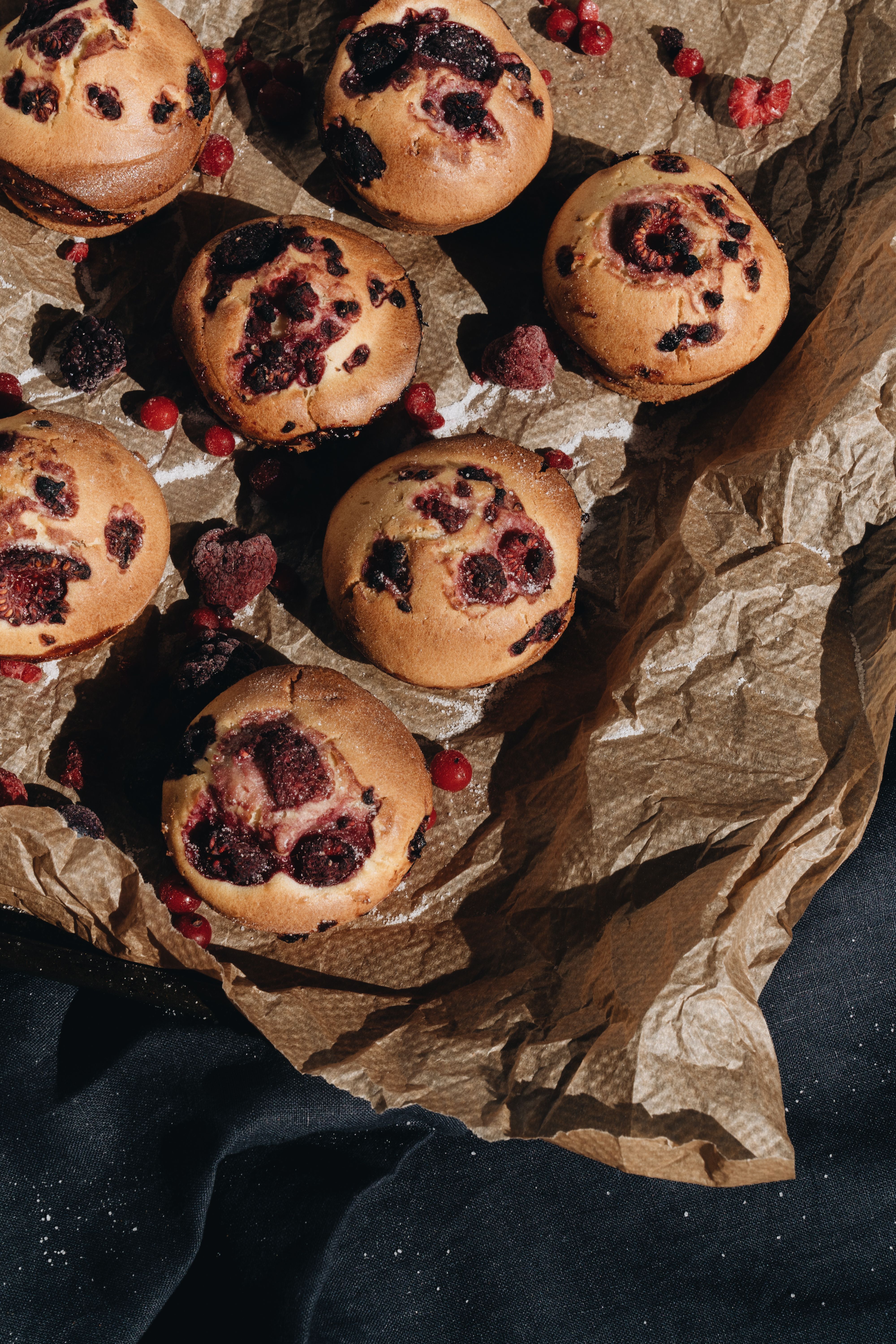 Delicious homemade berry muffins placed on rustic kraft paper, capturing the essence of traditional baking.