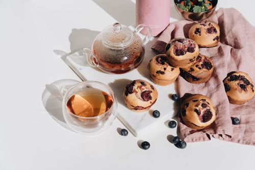 Free Delicious blueberry muffins paired with herbal tea on a marble slab. Perfect for breakfast or snack. Stock Photo