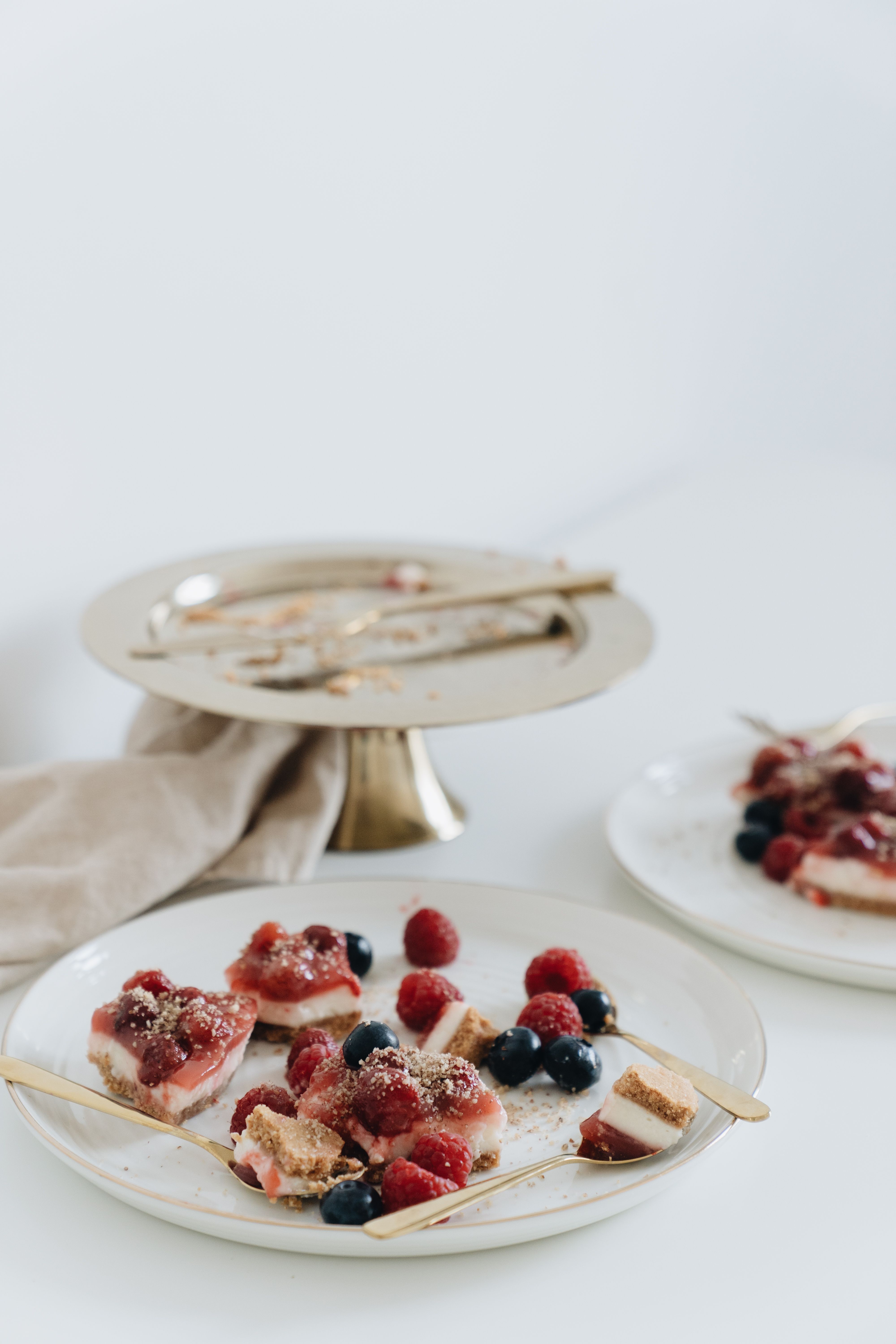 Close-up of berry-topped desserts on elegant plates with gold cutlery, perfect for a sweet treat showcase.