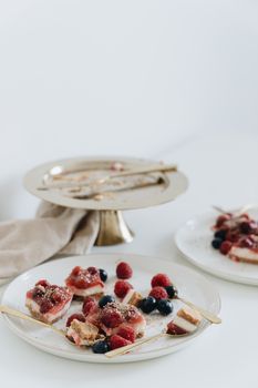 Close-up of berry-topped desserts on elegant plates with gold cutlery, perfect for a sweet treat showcase.