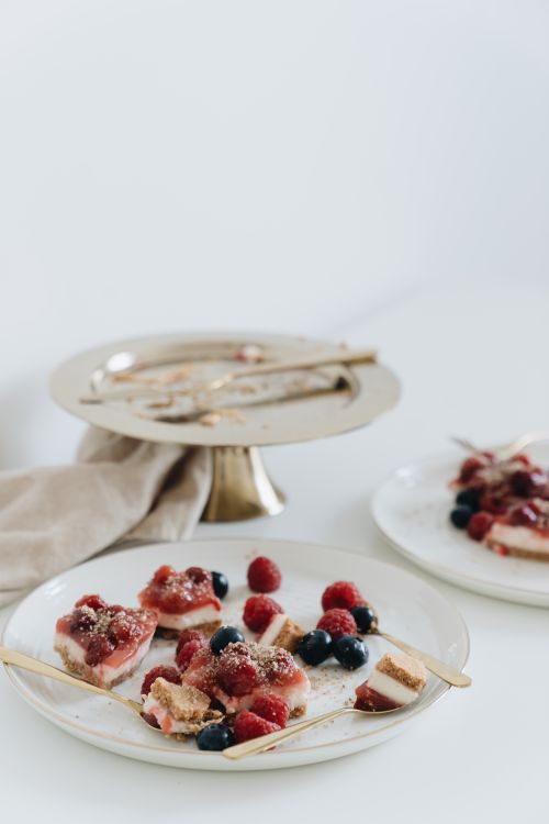 Free Close-up of berry-topped desserts on elegant plates with gold cutlery, perfect for a sweet treat showcase. Stock Photo