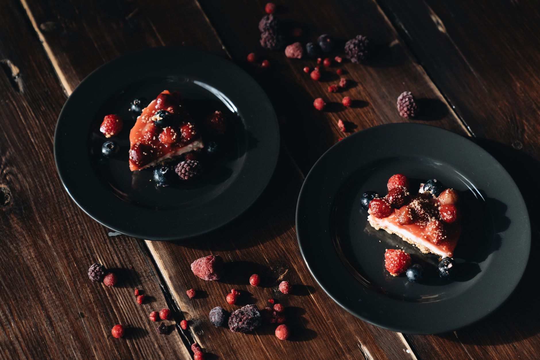 Rich vegan cheesecake topped with fresh berries and mint on wooden table