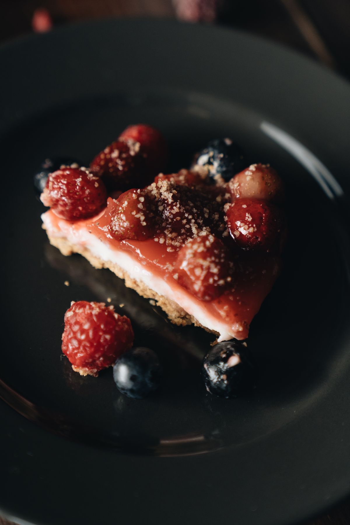 Cheesecake slice topped with fresh raspberries and blueberries