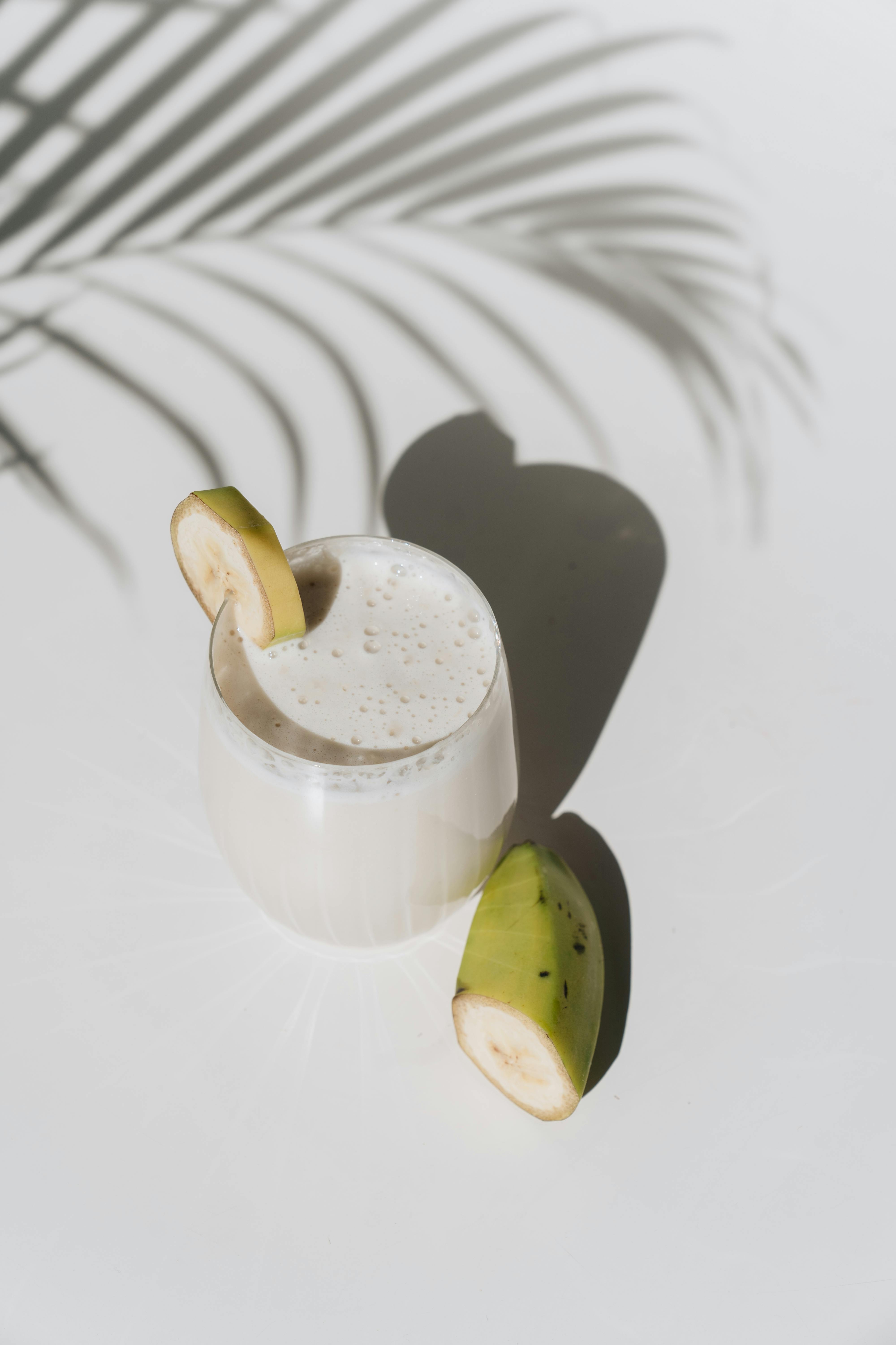 A delicious banana smoothie in bright sunlight with artistic shadows creating a tropical ambiance.