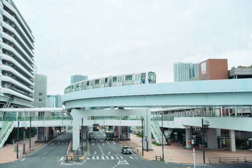 Free Elevated train passing through cityscape with modern buildings and roads. Stock Photo
