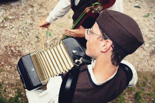 A person dressed in traditional attire playing an accordion at an outdoor event.