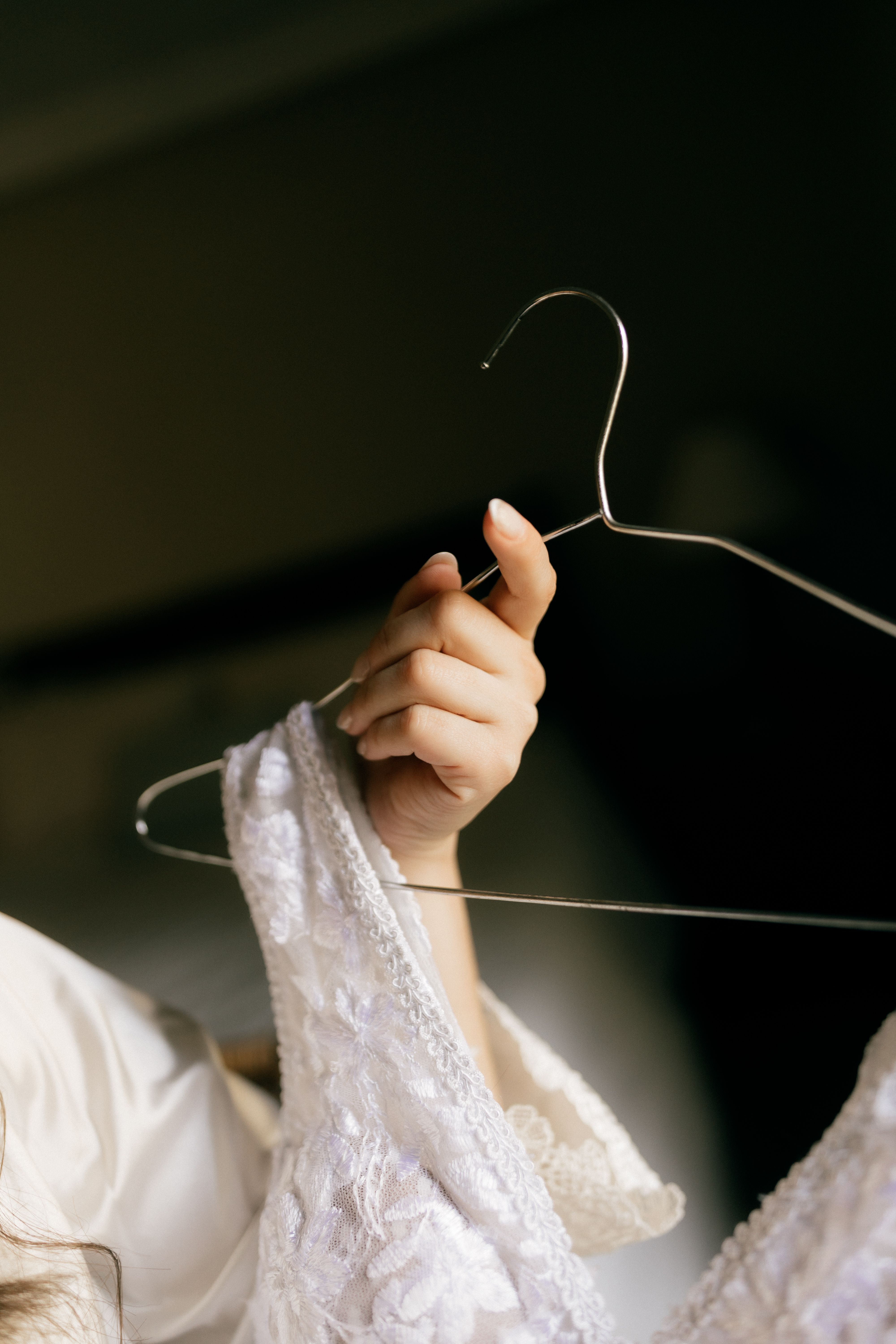 Elegant Hand Holding Wedding Dress on Hanger · Free Stock Photo