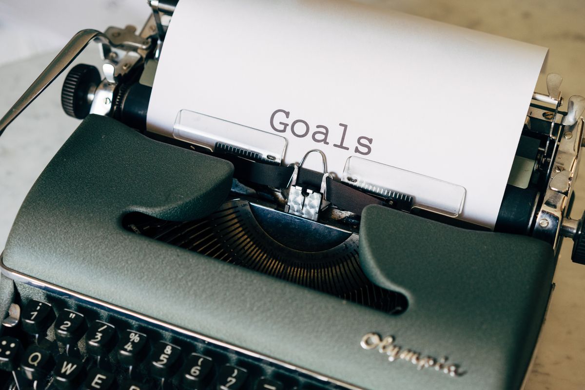 Máquina de escrever antiga com a palavra "Goals" digitada no papel, representando metas financeiras
