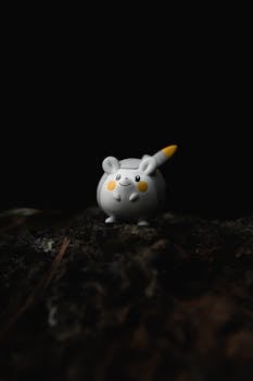 Closeup of small rubber spherical anime character toy placed on rough surface against black background