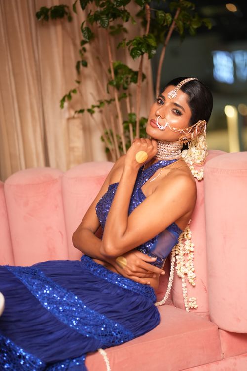 Free Stunning woman in sparkling blue ethnic outfit with traditional jewelry on pink sofa. Stock Photo