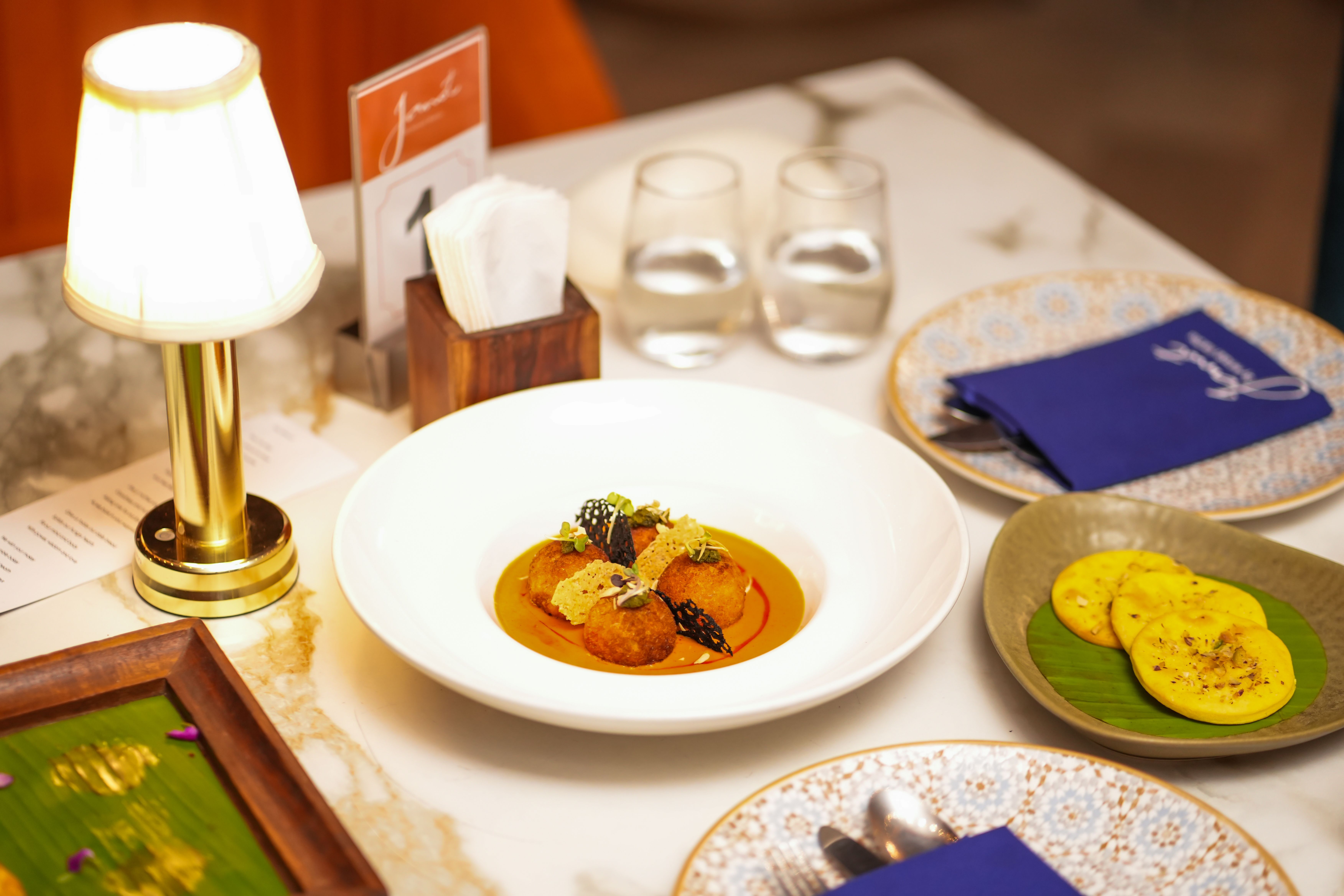 An elegant dining room with plated Indian dishes and candlelight