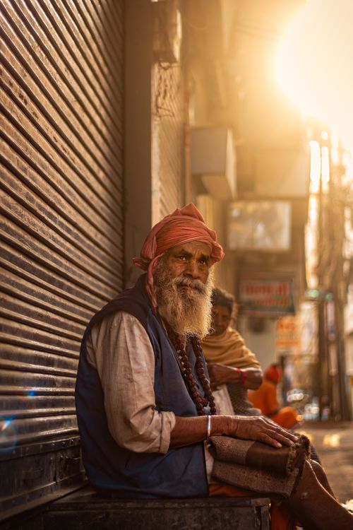 Free Elderly man with headscarf sitting on an Indian street in soft sunlight, wearing a beaded necklace. Stock Photo