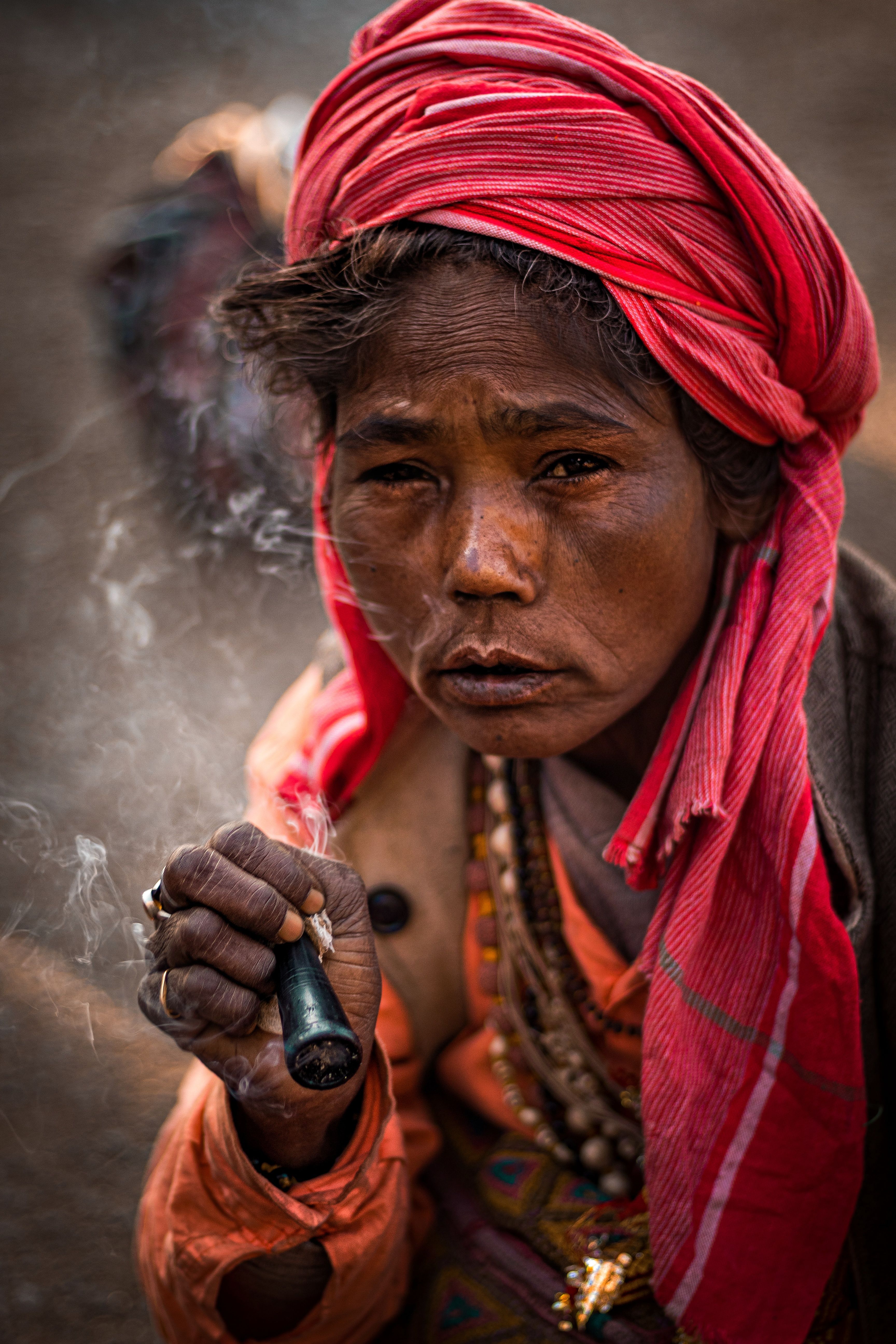 Close-up portrait of a woman in traditional Indian attire smoking, showcasing vibrant culture.