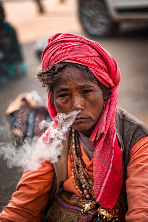 Ethnic woman in traditional turban smoking on street
