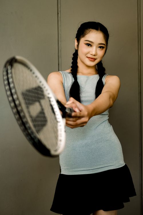 Free Young woman with braided hair posing in a tennis outfit, extending racket forward. Stock Photo