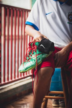 A close-up of a teenager tying vibrant sneakers with Nike logo indoors.