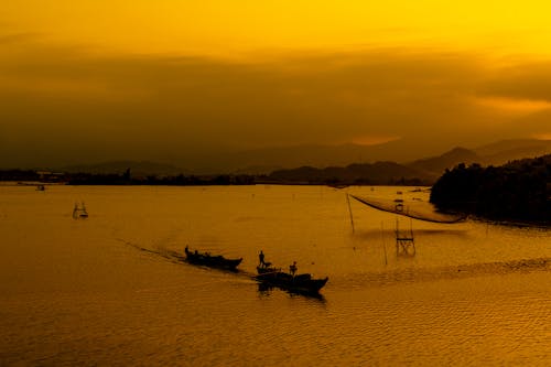 Silhouette of Fishing  Boats on Sea At Sunset
