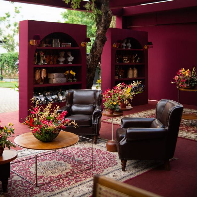 Stylish outdoor lounge with leather chairs, vibrant florals, and burgundy decor.