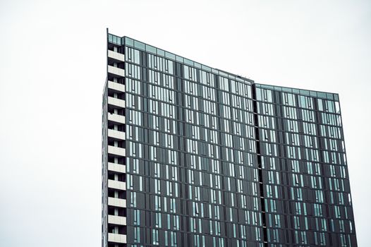 Low-angle view of a modern skyscraper with a glass facade against a clear sky.