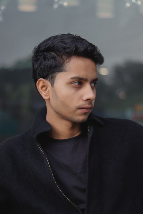 Free Portrait of a thoughtful young man looking away, captured in an urban environment. Stock Photo
