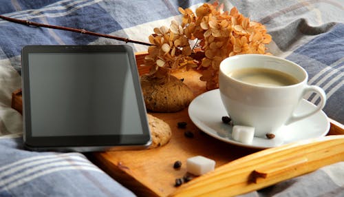 White Ceramic Cup on Saucer Beside Black Ipad