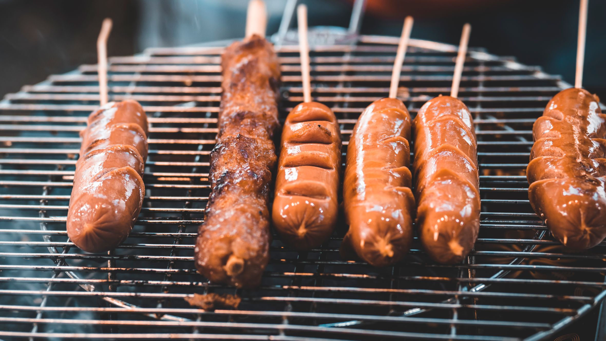 Close-up of delicious sausages cooking on a smoky BBQ grill. Perfect for food photography enthusiasts.