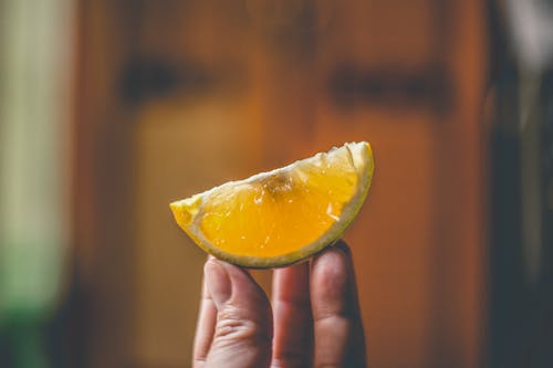 Photo Of Person Holding Sliced Lemon Fruit