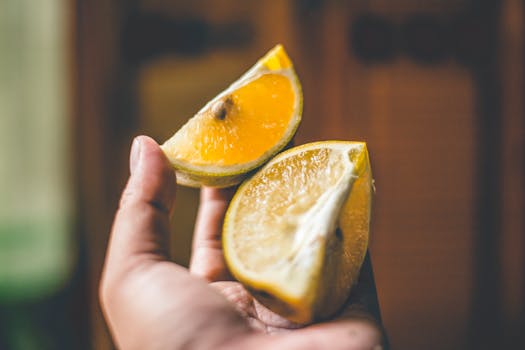 A detailed close-up of a hand holding vibrant lemon slices, showcasing freshness and natural texture.
