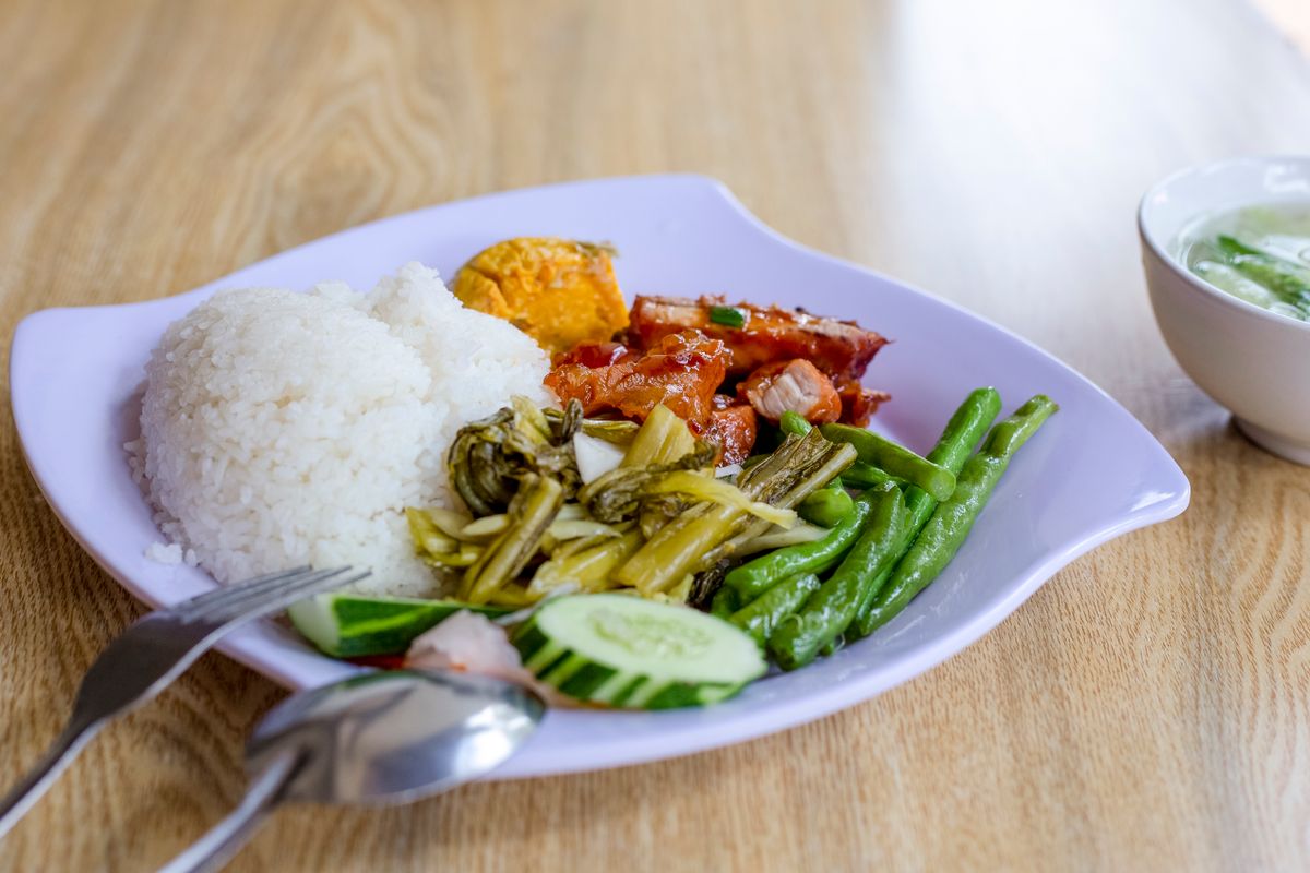 A plate of white rice served with vegetables, egg and meat.