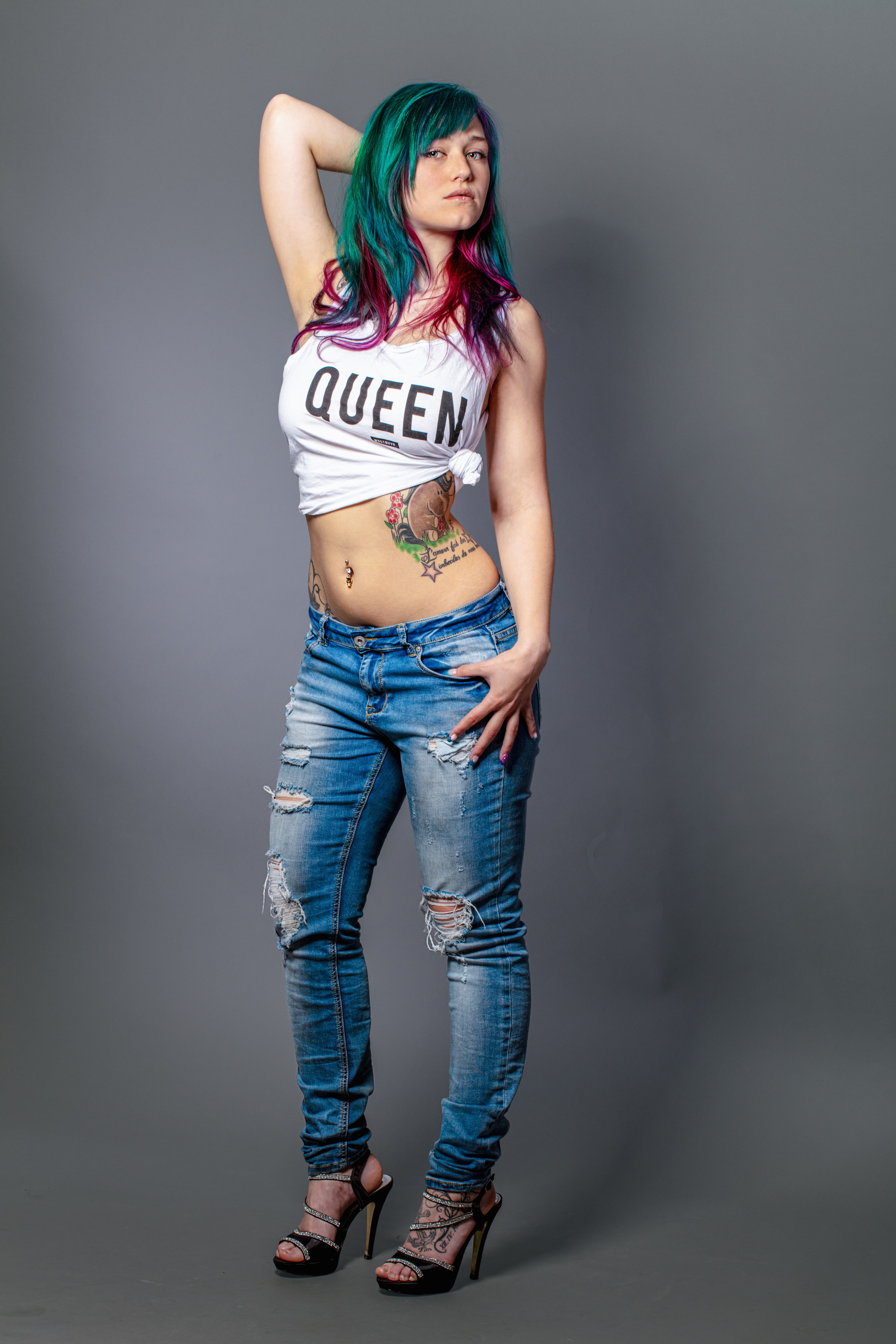 Portrait of a stylish young woman with colorful hair and tattoos posing confidently.