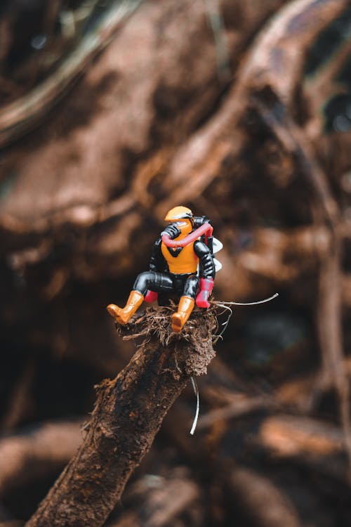 Free Small comic hero figurine placed on tree trunk Stock Photo