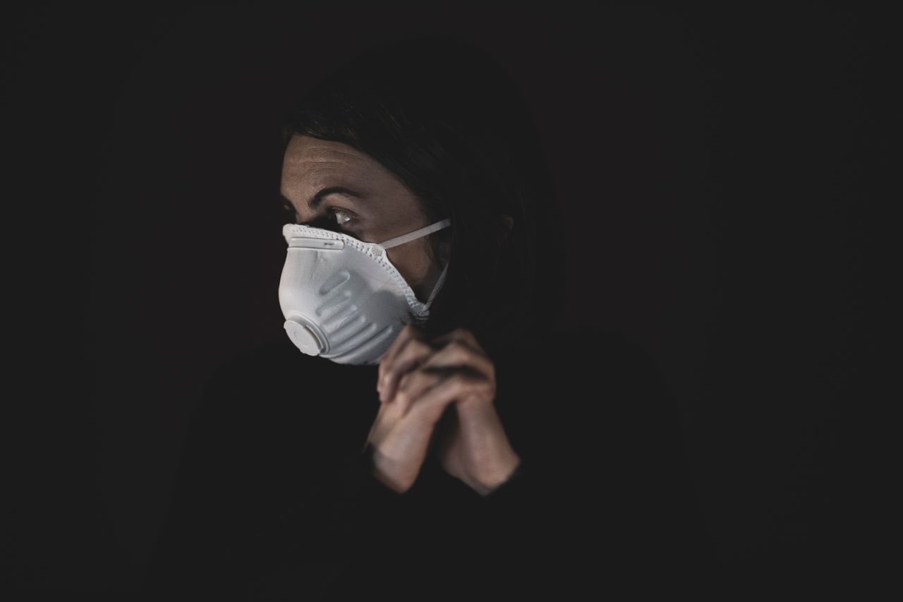 close up of a woman wearing a protective mask in a dark studio conveyi
