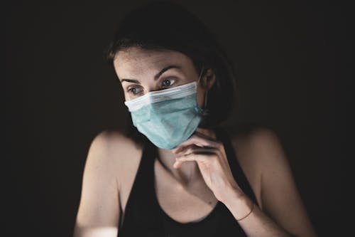 Woman in Black Tank Top Covering Her Face With Blue and White Mask