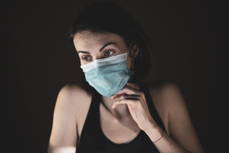 Woman In Black Tank Top Covering Her Face With Blue And White Mask