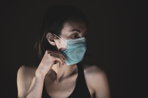 Woman in Black Tank Top Wearing A Surgical Mask