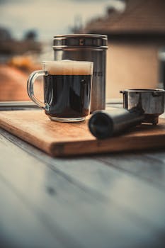 A cozy rustic coffee scene featuring a steaming mug, grinder, and container on a wooden board.