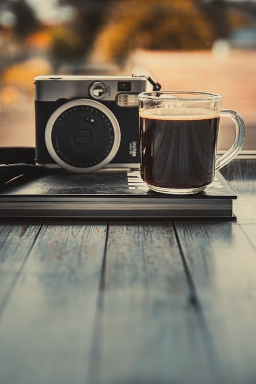 Glass Mug With Coffee Beside An Old Camera