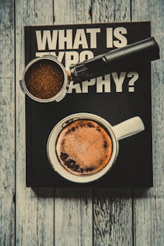 A warm coffee cup and grounds on a typography book on a rustic wooden table.
