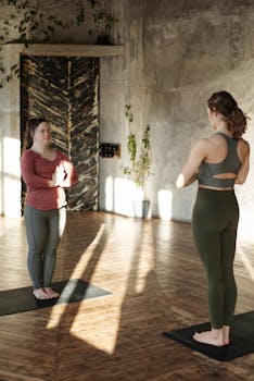 Two women practicing yoga indoors, focusing on concentration and relaxation.