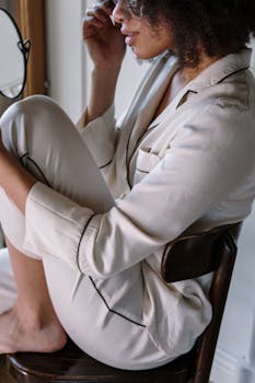 A woman in soft pajamas seated by a window, embracing a calm morning routine.