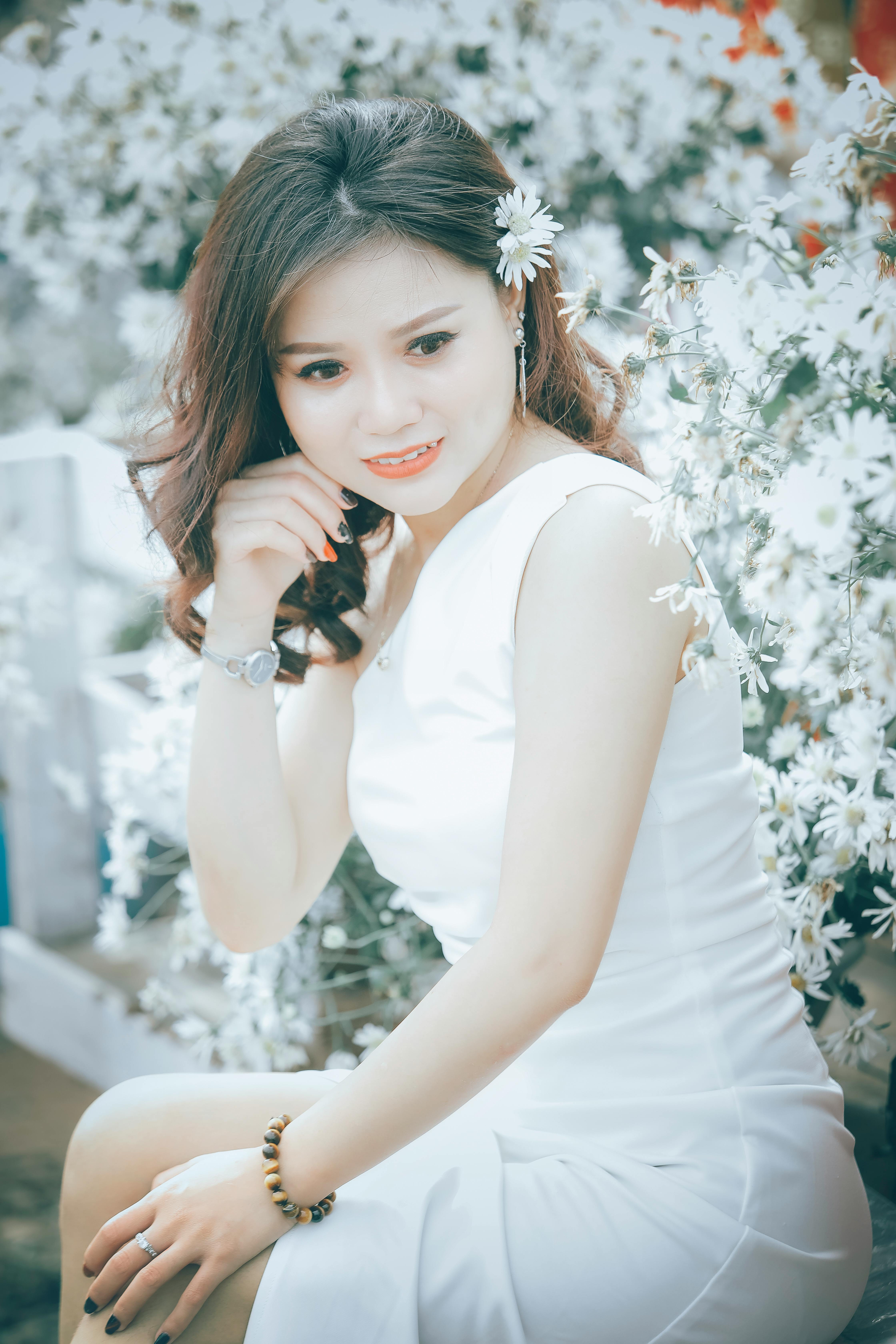 一位白衣美女优雅地坐在盛开的白花丛中