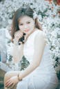 一位白衣美女优雅地坐在盛开的白花丛中