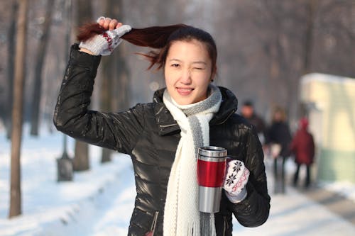 女人抱着头发和红色和灰色的旅行杯