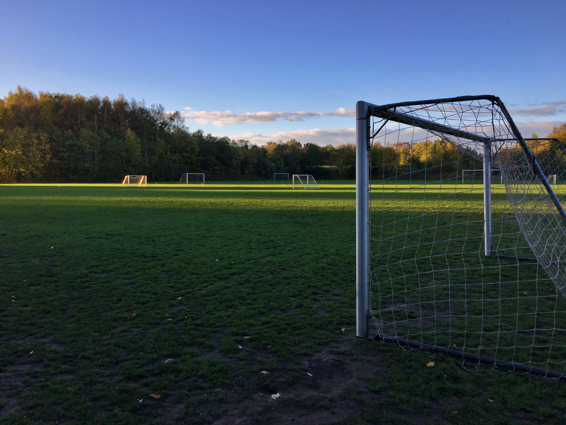 Empty football pitch with goal posts in evening light