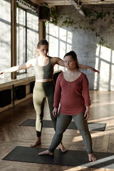 Two women practicing yoga indoors, highlighting inclusivity and wellness.