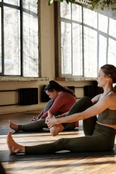 Two women engaging in a yoga session in a bright, peaceful studio setting.