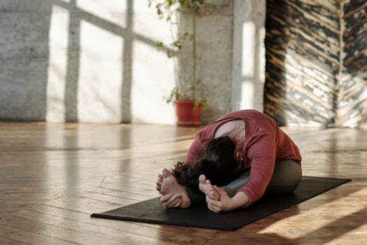 A woman stretches on a yoga mat in a sunlit room, embracing relaxation and wellness.